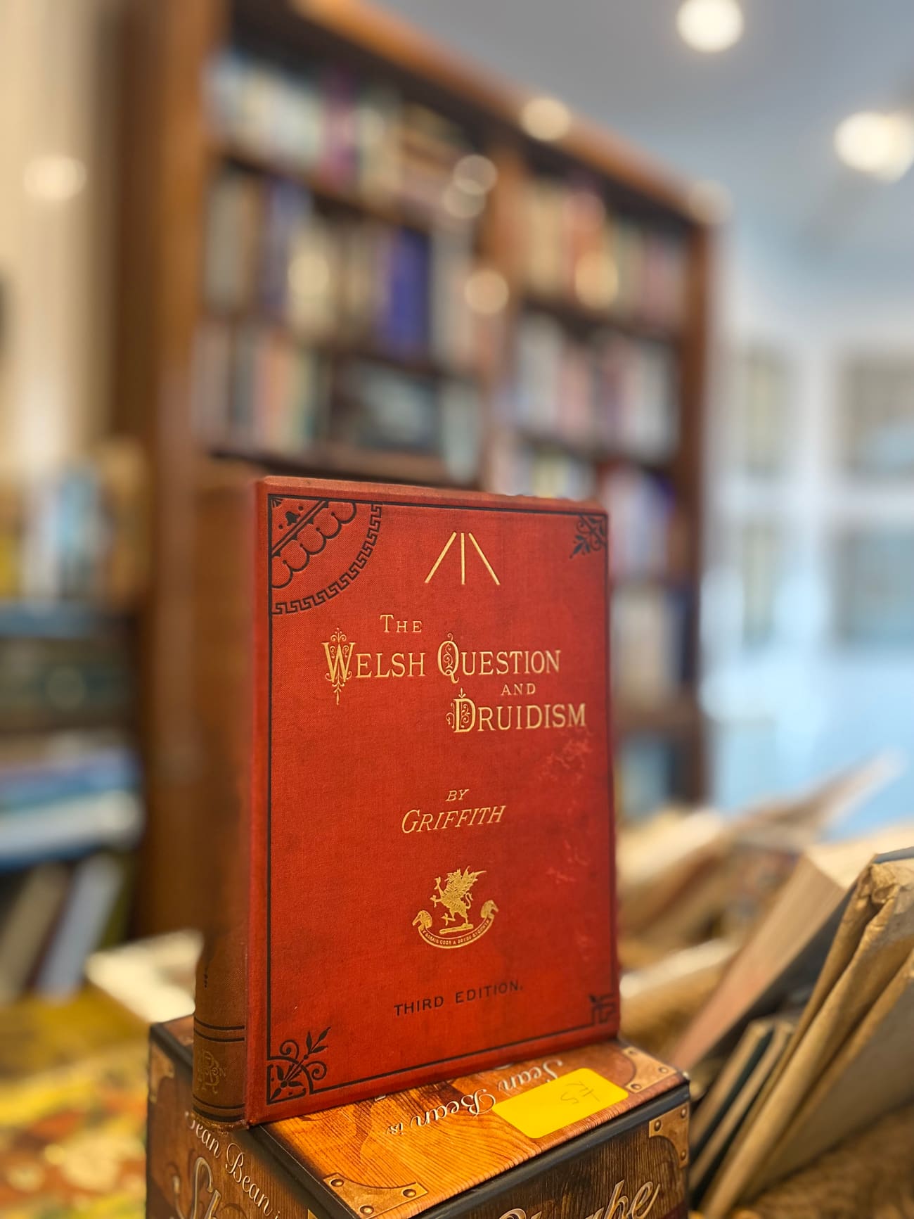 An older red cloth-bound book displayed among other volumes